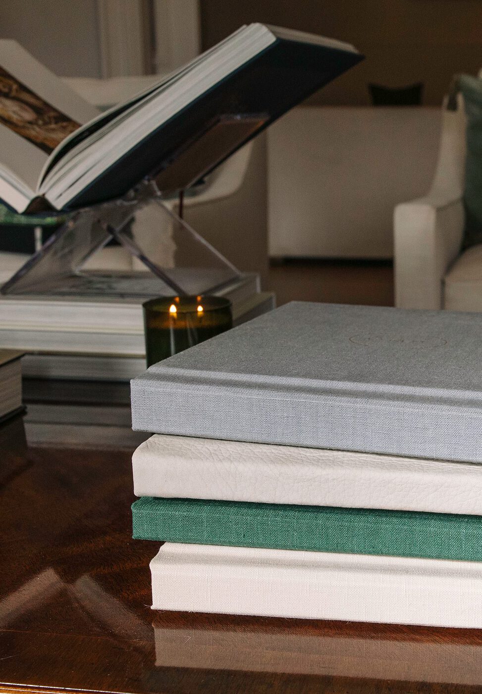 A stack of albums in different cover materials beside an open album on a stand